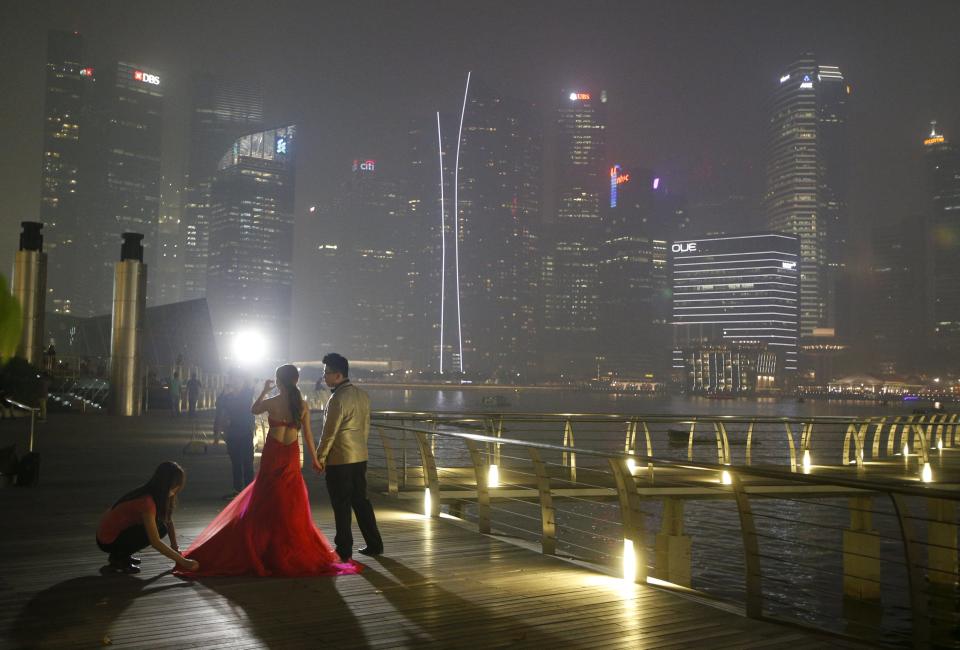 A couple have their wedding photos taken in the backdrop of the haze-shrouded central business district in Singapore