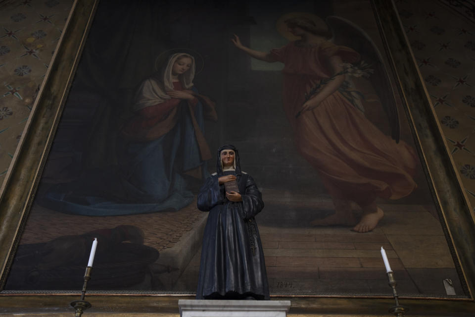 A statue of Saint Louise de Marillac, co-founder of the Daughters of Charity, stands in front of a painting of the Annunciation of Theotokos inside a complex of Catholic buildings that includes the cathedral, a church and the Monastery of St. Catherine on the Greek island of Santorini on Tuesday, June 14, 2022. (AP Photo/Petros Giannakouris)