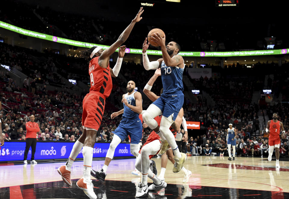Minnesota Timberwolves guard Mike Conley, right, drives to the basket against Portland Trail Blazers forward Jerami Grant during the first half of an NBA basketball game in Portland, Ore., Tuesday Feb. 13, 2024. (AP Photo/Steve Dykes)