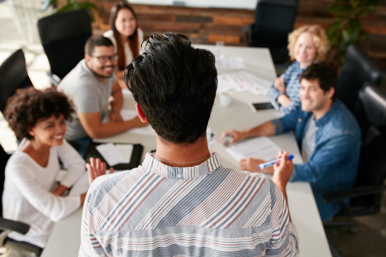 Rear view portrait of man explaining business ideas to colleagues during a meeting in conference room.  Young people meeting in boardroom.