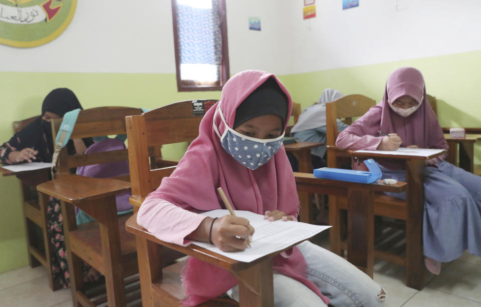 Students wearing face masks sit spaced apart during a trial run of a class with COVID-19 protocol at the Nurul Amal Islamic school in Tangerang, Indonesia, Monday, Nov. 23, 2020. (AP Photo/Tatan Syuflana)