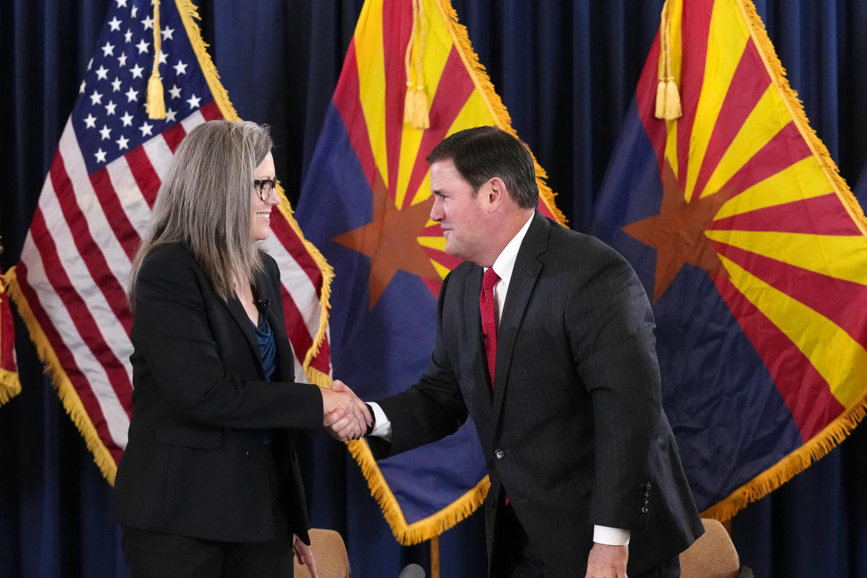 Arizona Democrat governor-elect and current Arizona Secretary or State Katie Hobbs, left, shakes hands with Arizona Republican Gov. Doug Ducey, right, after the official certification for the Arizona general election canvass in a ceremony at the Arizona Capitol in Phoenix, Monday, Dec. 5, 2022. (AP Photo/Ross D. Franklin, Pool)