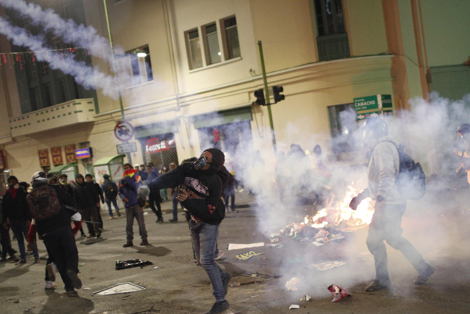 A protester against the reelection of President Evo Morales hurls a tear gas canister back at police during clashes in La Paz, Bolivia, Thursday, Oct. 31, 2019. Violence has escalated since Morales was declared the winner of the Oct. 20 vote amid delays in the vote count. The opposition alleges the outcome was rigged to give Morales enough of a majority to avoid a runoff election; the president denies any irregularities. (AP Photo/Juan Karita)