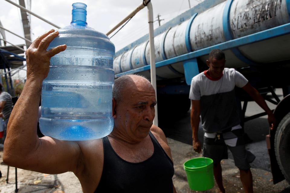 Men carry containers filled with water from a tank truck in the municipality of Canovanas, Puerto Rico, on Sept. 26. (Photo: Carlos Garcia Rawlins/Reuters)