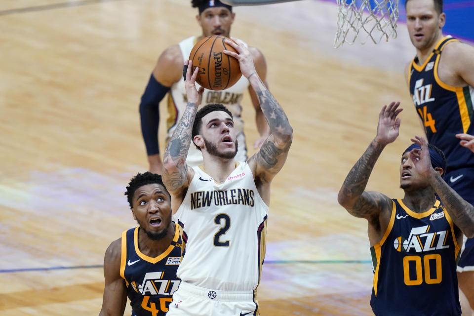 New Orleans Pelicans guard Lonzo Ball (2) goes to the basket between Utah Jazz guard Donovan Mitchell (45) and guard Jordan Clarkson (00) in the first half of an NBA basketball game in New Orleans, Monday, March 1, 2021. (AP Photo/Gerald Herbert)