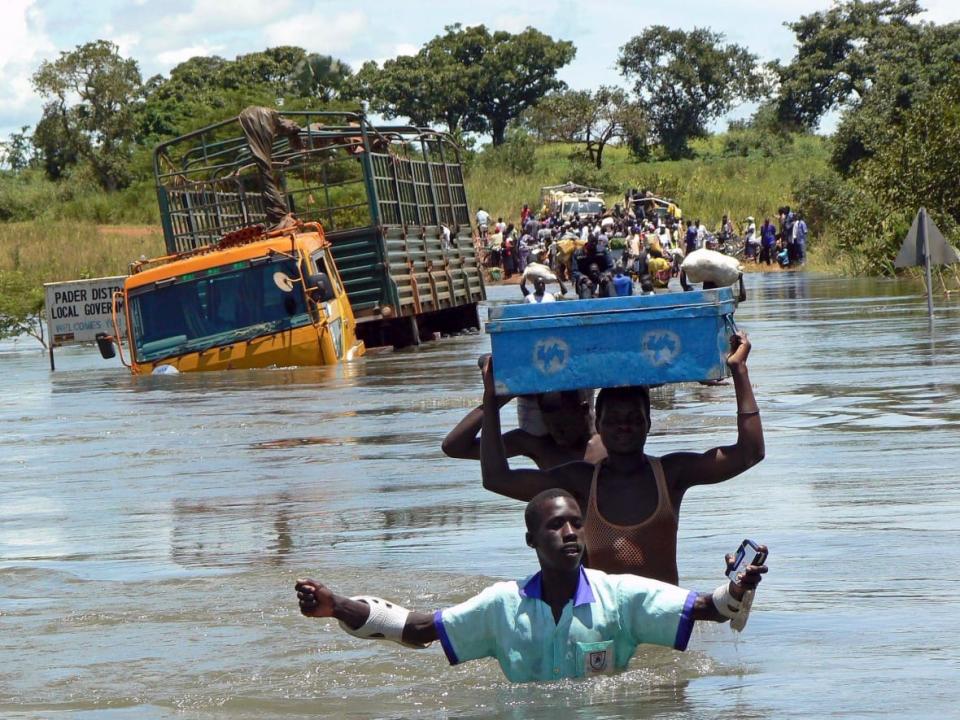 Ugandans move through floodwaters in the town of Lira in September 2007. (Hudson Apunyo/Reuters - image credit)