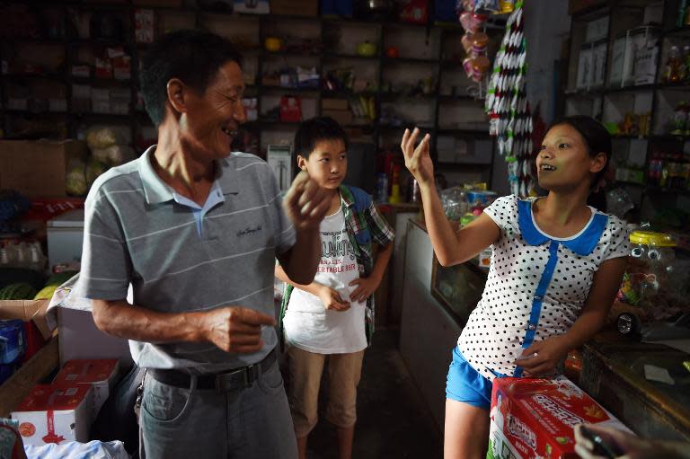 Vietnamese bride Vu Thi Hong Thuy chats with Chinese customers in the shop where her friend, also Vietnamese, works in Weijian village, China's Henan province on July 29, 2014