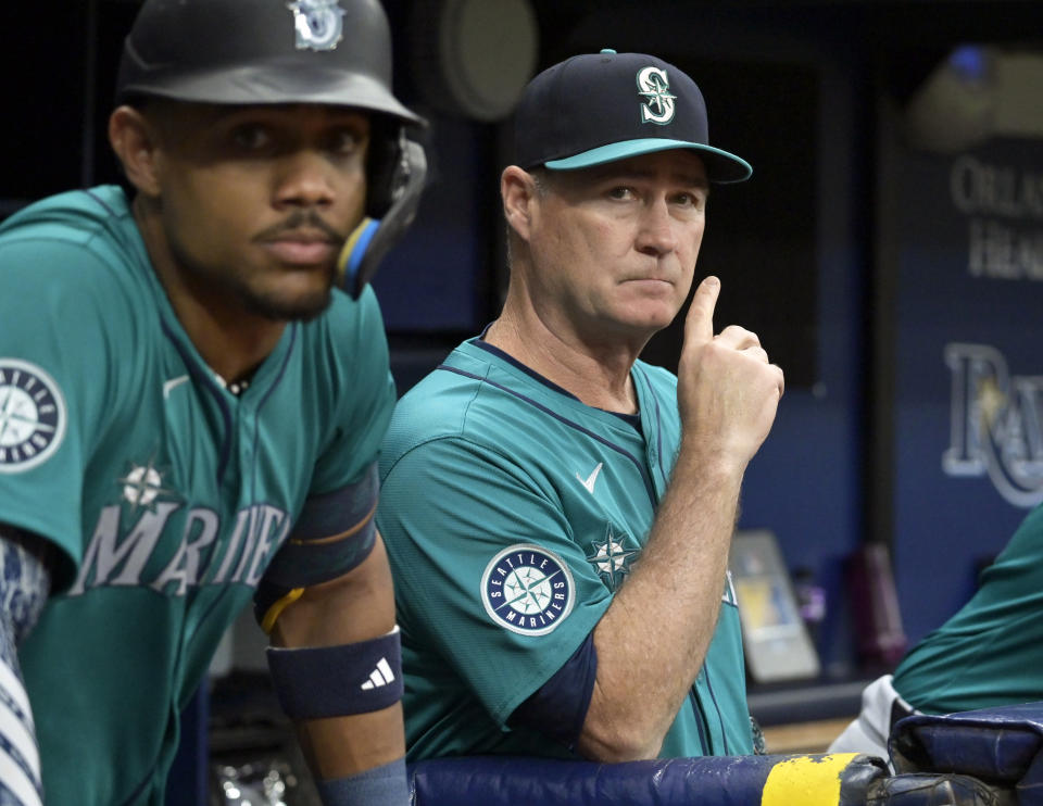 Seattle Mariners manager Scott Servais, right, and Julio Rodríguez, left, watch from the dugout during the first inning of a baseball game against the Tampa Bay Rays, Monday, June 24, 2024, in St. Petersburg, Fla. (AP Photo/Steve Nesius)