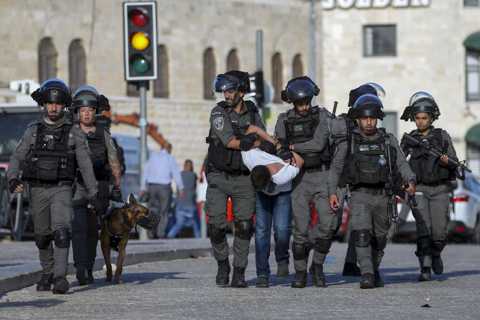 Israeli border police officers detain a Palestinian youth during clashes between Palestinians and Israeli police as thousands of Muslims flocked to Jerusalem's Old City to celebrate the Prophet Muhammad's birthday, Tuesday, Oct. 19, 2021. (AP Photo/Mahmoud Illean)