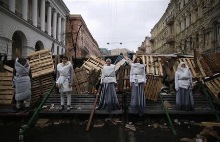 Models pose at a barricade as they take part in a photo shoot for an art project, at Independence Square in Kiev December 7, 2013. REUTERS/Stoyan Nenov