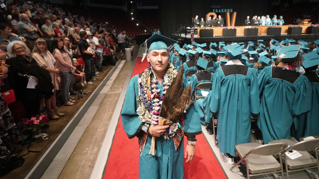 Dayne Hudson, member of the Paiute Indian Tribe of Utah, walks with his eagle feather fan during the Canyon View High School graduation Wednesday, May 25, 2022, in Cedar City, Utah. Hudson said it was important to wear eagle feathers and a beaded cap to represent his family and honor those who were stopped from doing so under the old rule. (AP Photo/Rick Bowmer)