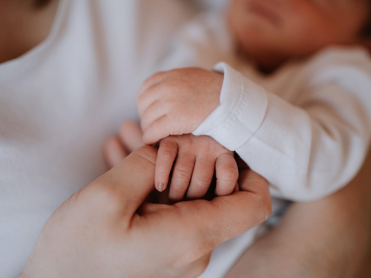 Close up photo of a mother holding a newborn baby son at home.