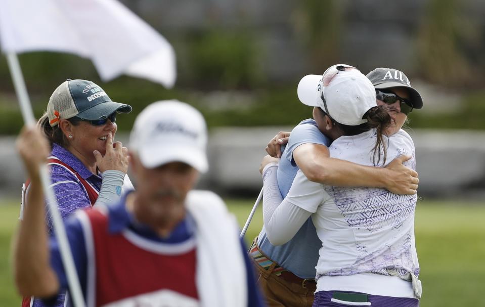 Jasmine Suwannapura (back to camera), of Thailand, hugs teammate Cydney Clanton after finishing the third round of the Dow Great Lakes Bay Invitational golf tournament, Friday, July 19, 2019, in Midland, Mich. (AP Photo/Carlos Osorio)