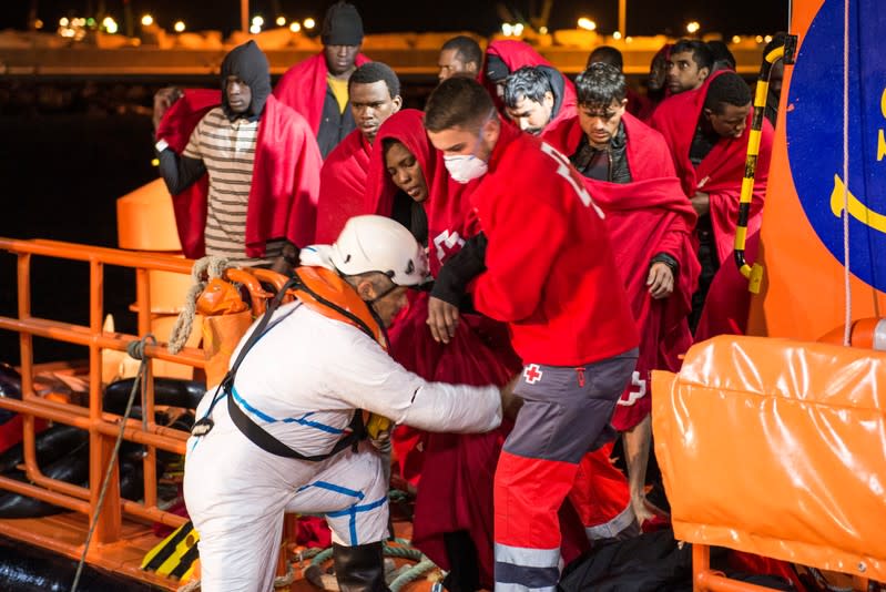 A Spanish coast guard and a member of the Spanish Red Cross help disembark migrants after dozens of them were rescued in a raft off the coast at the Mediterranean Sea, at the port of the Spanish North African enclave of Melilla