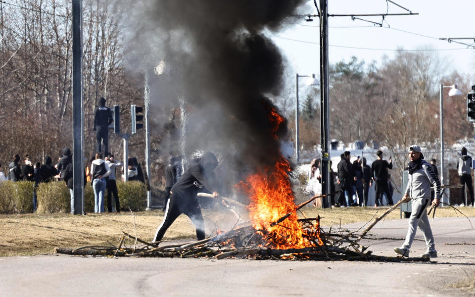 People burn branches to block a road during a riot in Norrkoping, Sweden, Sunday, April 17, 2022. Unrest has broken out in southern Sweden despite police moving a rally by an anti-Islam far-right group, which was planning to burn a Quran among other things, to a new location as a preventive measure. (Stefan Jerrevang/TT News Agency via AP)