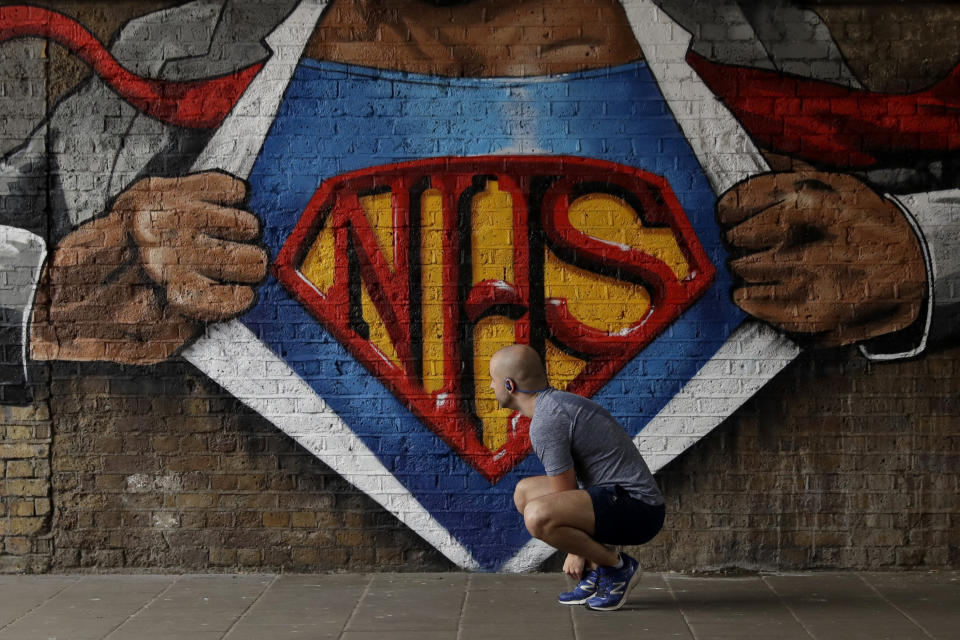 A jogger stops to tie his shoelace next to a recently painted NHS (National Health Service) Superman design mural by street artist Lionel Stanhope during the coronavirus lockdown, in the Waterloo area of London, Sunday, May 3, 2020. The highly contagious COVID-19 coronavirus has impacted on nations around the globe, many imposing self isolation and exercising social distancing when people move from their homes. (AP Photo/Matt Dunham)