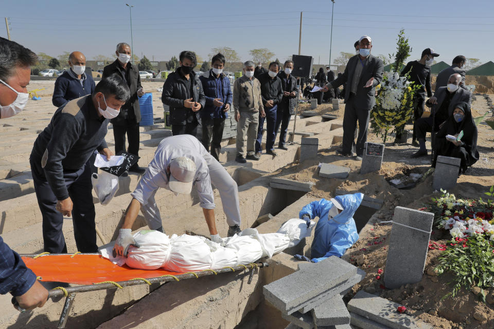 The body of a person who died from COVID-19 is interred as mourners look on, at the Behesht-e-Zahra cemetery on the outskirts of Tehran, Iran, Sunday, Nov. 1, 2020. (AP Photo/Ebrahim Noroozi)