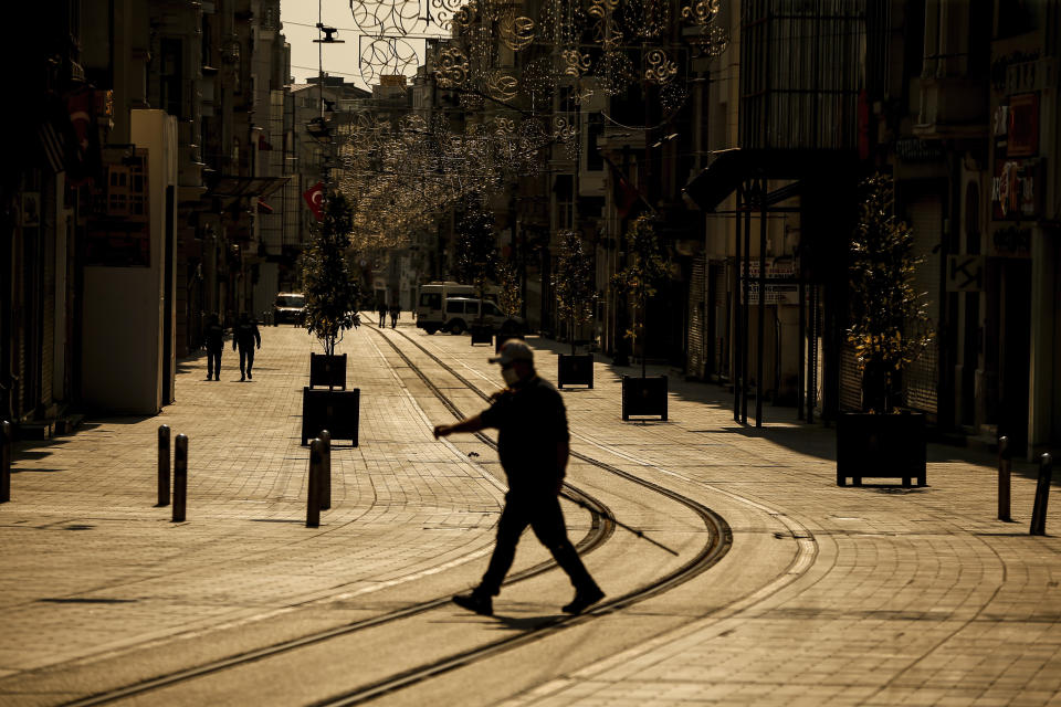 A man walks in the normally crowded but now mostly deserted Istiklal Street hours after the two-day curfew declared by the government to slow coronavirus spread, in Istanbul, Saturday, April 11, 2020. The new coronavirus causes mild or moderate symptoms for most people, but for some, especially older adults and people with existing health problems, it can cause more severe illness or death.(AP Photo/Emrah Gurel)
