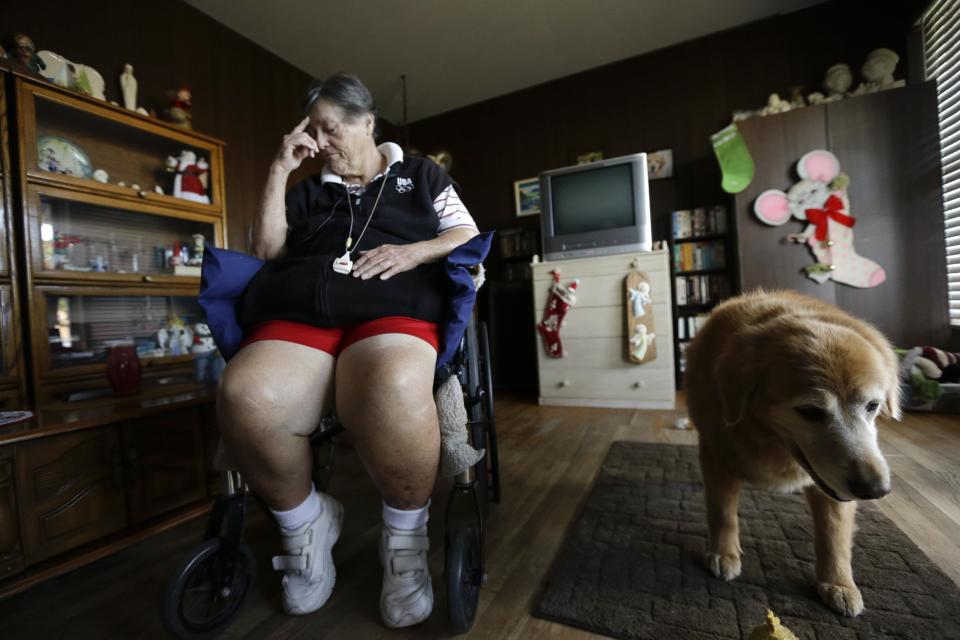 In this Dec. 10, 2013 image, Sherry Scott sits in a wheel chair, alongside her 10-year-old golden retriever Tootie, at her home in San Diego. Scott, who receives dog food for Tootie through the Animeals program, said she would give her lasagne and pork riblets from Meals on Wheels to Tootie if MOW didn't bring dog food for the dog. The pet food program is sponsored by the Helen Woodward Animal Center. (AP Photo/Gregory Bull)