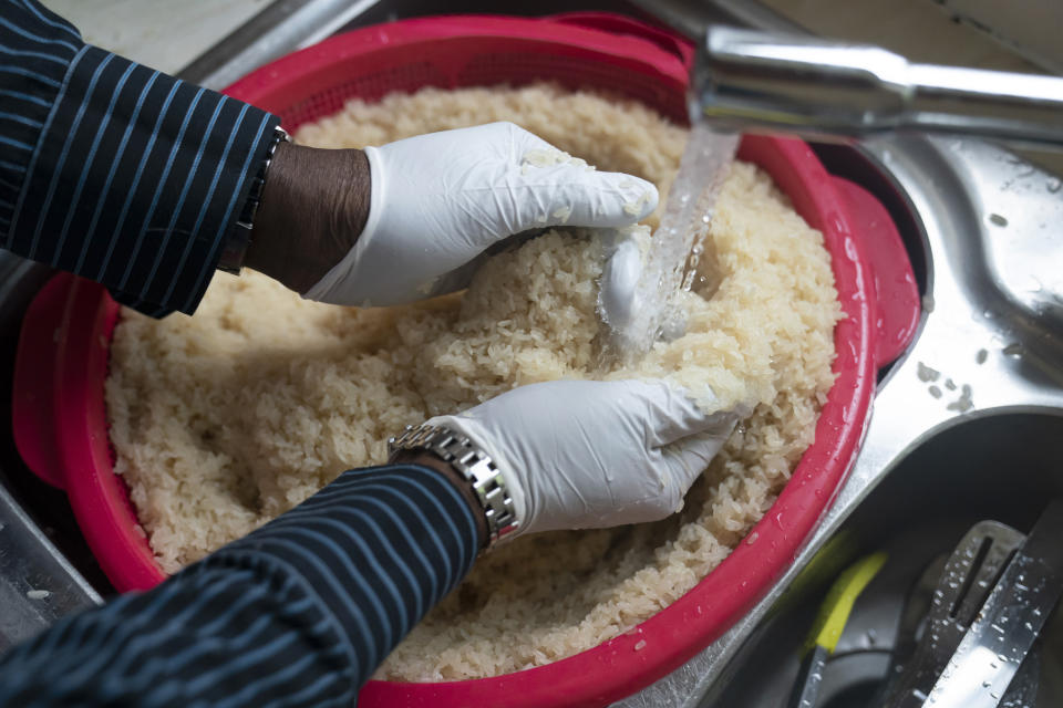 Volunteer Dave Williams washes rice as members of the Preston Windrush Covid Response team prepare West Indian meals, at the Xaverian Sanctuary, in Preston, England, Friday Feb. 19, 2021. Once a week chief coordinator Glenda Andrew and her team distribute meals to people in Preston and surrounding communities in northwestern England that have recorded some of the U.K.’s highest coronavirus infection rates. The meal program grew out of Andrew’s work with Preston Windrush Generation & Descendants, a group organized to fight for the rights of early immigrants from the Caribbean and other former British colonies who found themselves threatened with deportation in recent years. (AP Photo/Jon Super)