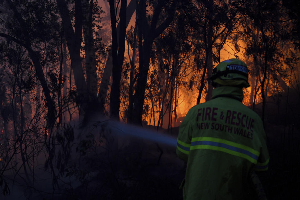 Fire and Rescue NSW firefighters conduct property protection as a bushfire burns close to homes on Railway Parade in Woodford NSW, Friday, Nov. 8, 2019. Firefighters battled 90 fires across Australia's most populous state, New South Wales, with the most intense in the northeast where flames have been fanned by strong winds, Rural Fire Service Commissioner Shane Fitzsimmons said.(Dan Himbrechts/AAP Image via AP)