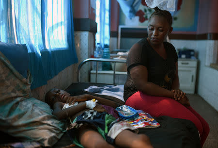 Khadija Kamara sits next to her son Carlos, who she says hasn't been seen by staff at Freetown's Connaught Hospital in days, despite needing surgery to remove a foreign object lodged in his windpipe, in Freetown, Sierra Leone December 12, 2018. REUTERS/Cooper Inveen