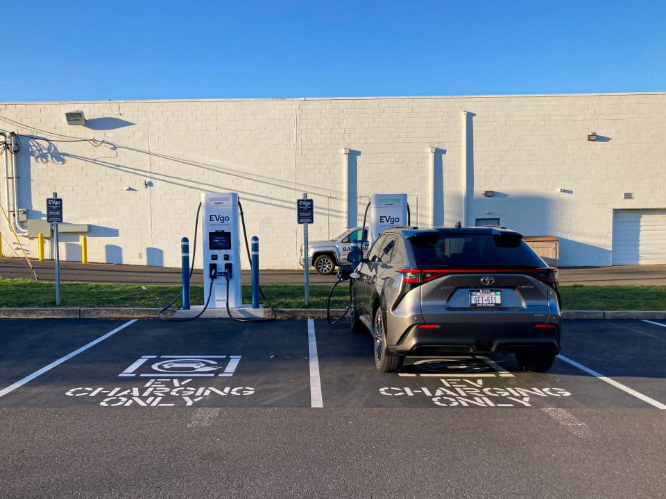 The 2023 Toyota bZ4X AWD Limited electric SUV parked in a parking lot, with a white building and blue skies in the background.