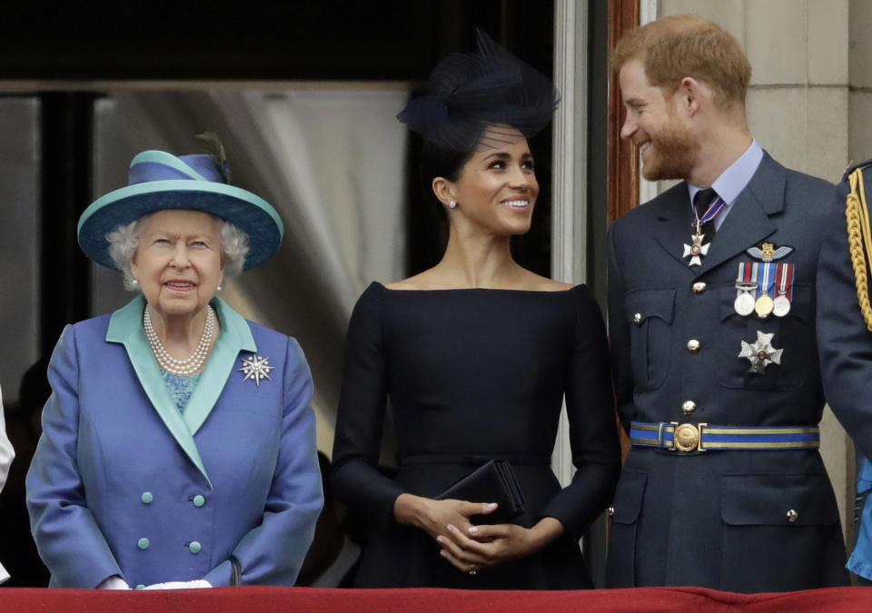 FILE - In this Tuesday, July 10, 2018 file photo Britain's Queen Elizabeth II, and Meghan the Duchess of Sussex and Prince Harry watch a flypast of Royal Air Force aircraft pass over Buckingham Palace in London. Prince Harry and Meghan Markle are to no longer use their HRH titles and will repay £2.4 million of taxpayer's money spent on renovating their Berkshire home, Buckingham Palace announced Saturday, Jan. 18. 2020. (AP Photo/Matt Dunham, File)