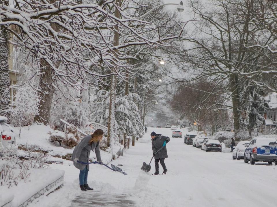 People shovel snow on a residential street in Toronto during Wednesday's winter storm.  (Showwei Chu/CBC - image credit)