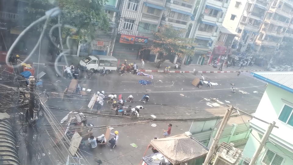 A wounded protester lies on the ground while others crouch behind a barricade amid protests against the military coup in Yangon, Myanmar February 28, 2021 in this screen grab obtained from a social media video. News Watch/via REUTERS THIS IMAGE HAS BEEN SUPPLIED BY A THIRD PARTY. MANDATORY CREDIT