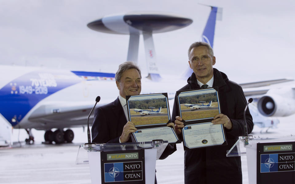 NATO Secretary General, Jens Stoltenberg, right, and the President of Boeing International, Sir Michael Arthur, hold up photos of an AWACS plane during a media conference at Melsbroek military airport in Melsbroek, Belgium, Wednesday, Nov. 27, 2019. NATO and the Boeing Company on Wednesday marked the signing of a 1 billion US dollar contract to modernize the Alliance's fleet of AWACS aircraft. This will ensure that NATO AWACS continue to support the Alliance's missions to 2035. (AP Photo/Virginia Mayo)