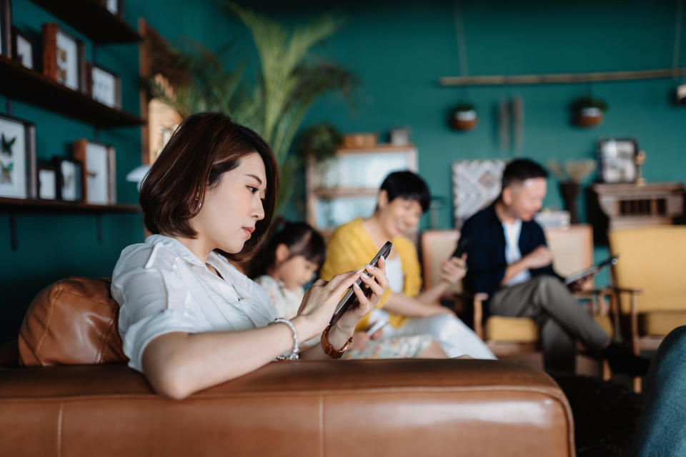 A woman is keeping to herself in the family living room