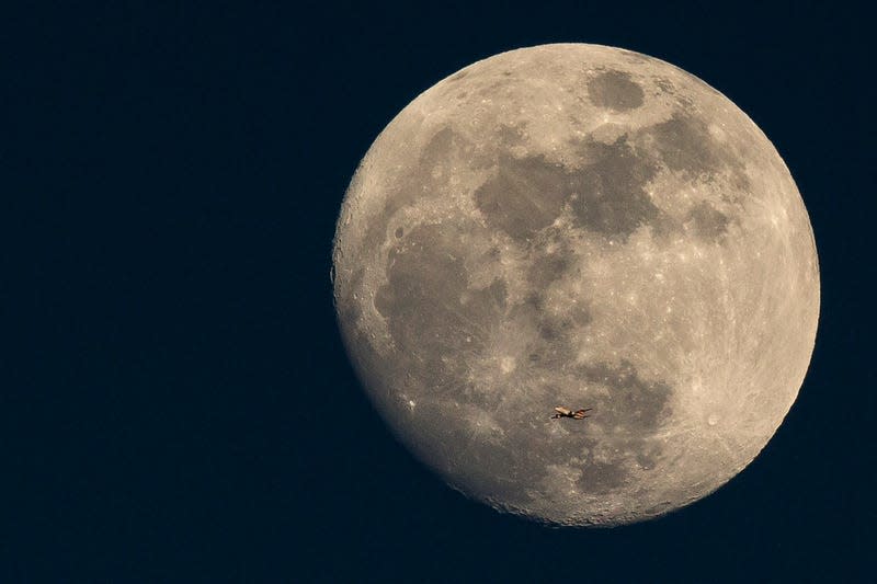 A plane passes in front of the Moon.