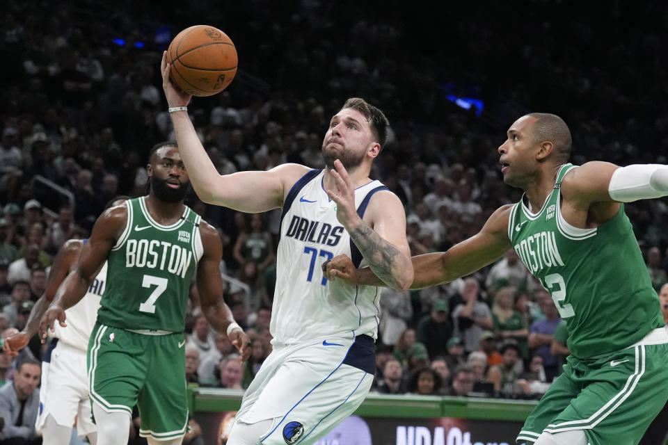 Dallas Mavericks guard Luka Doncic (77) drives as Boston Celtics guard Jaylen Brown (7) and center Al Horford, right, defend during the second half of Game 5 of basketball's NBA Finals, Monday, June 17, 2024, in Boston. (AP Photo/Charles Krupa)