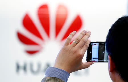 FILE PHOTO: A man takes a picture of a Huawei logo at the Huawei European Cybersecurity Center in Brussels, Belgium, May 21, 2019. REUTERS/Francois Lenoir/File Photo