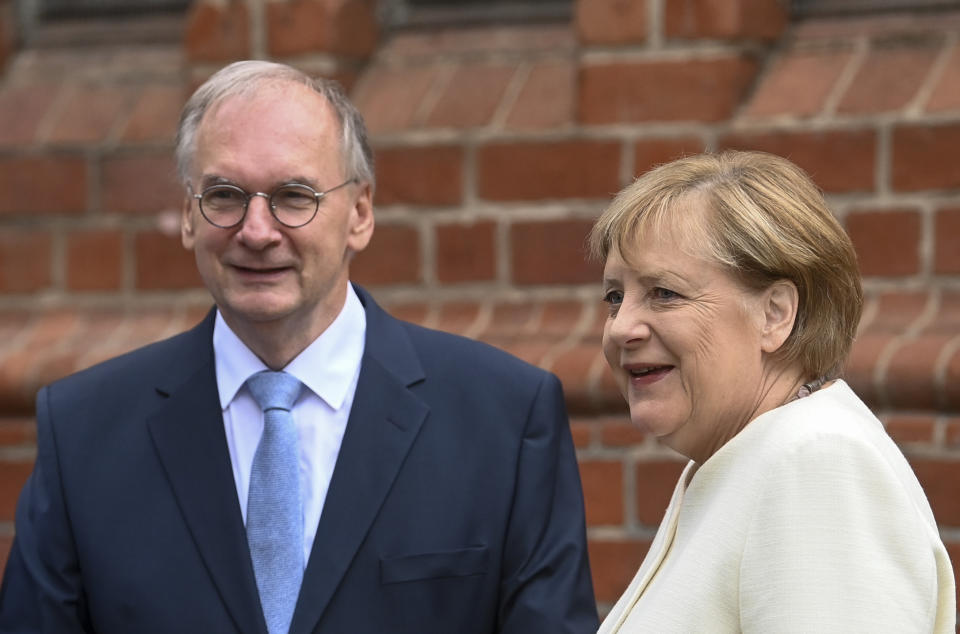 Reiner Haseloff (CDU), Minister President of Saxony-Anhalt, greets German Chancellor Angela Merkel (CDU) before the start of an ecumenical service at St. Paul's Church in Halle/Saale, Germany, at the central celebrations for the Day of German Unity on Sunday, Oct. 3, 2021. (Hendrik Schmidt/Pool via AP)