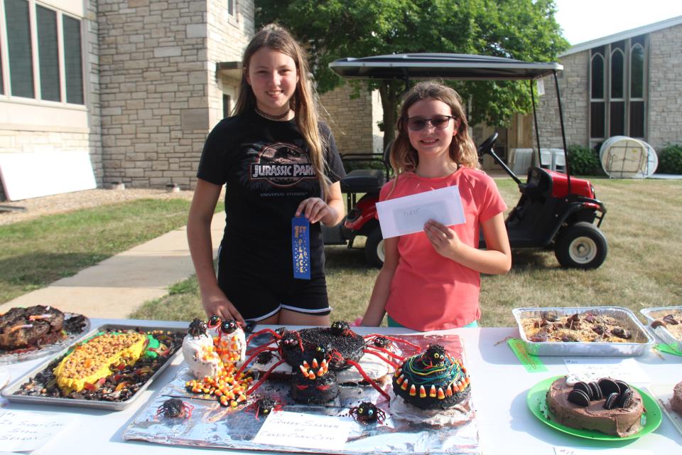 Sisters Hailey Swanson, 12, and Fiona Swanson, 9, pose for a photo with their winning ugly cake during the Dallas Center Fall Festival on Friday, Aug. 26, 2022.