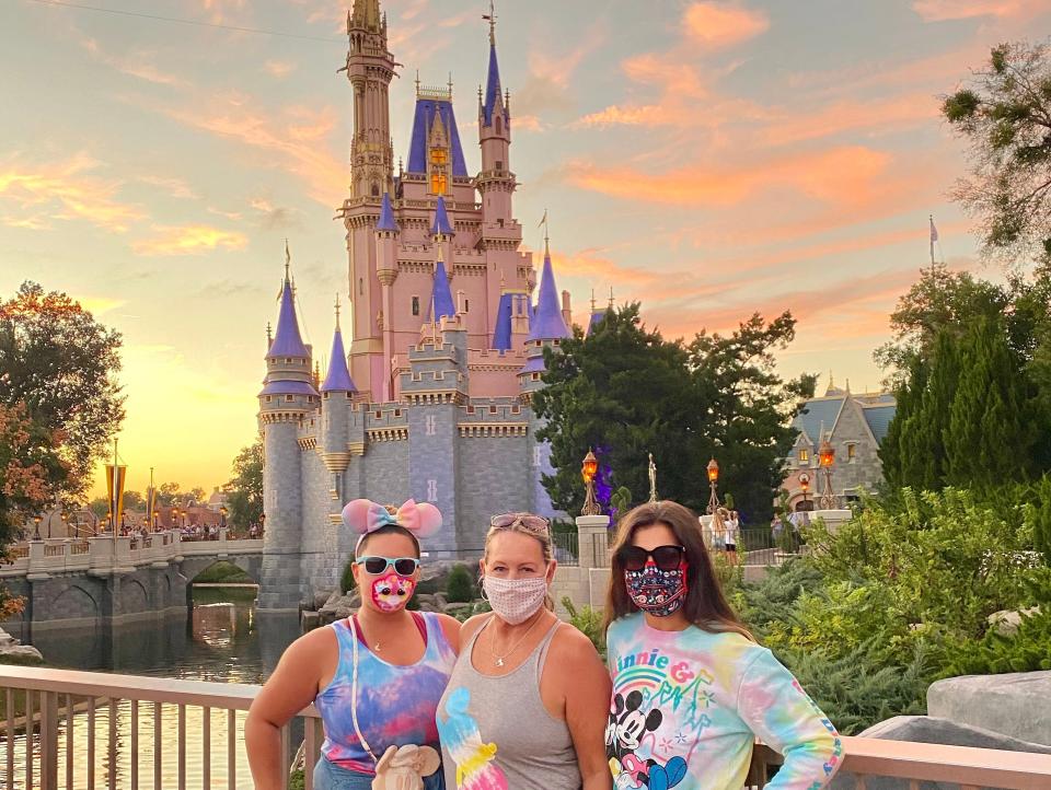 three women standing in front of cinderella castle at disney world