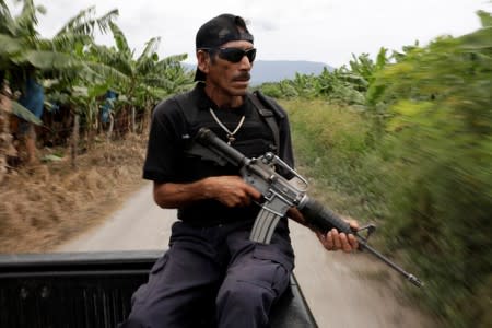 A vigilante rides on the back of a truck while patrolling the municipality of Coahuayana