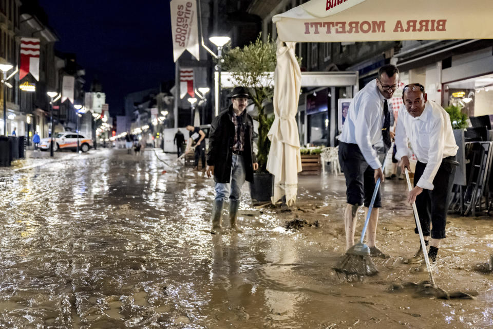 People clear mud from the flooded Grand-Rue following a storm that caused extensive flooding in the town centre on Tuesday 25 June 2024 in Morges, Switzerland. Clean-up crews and business owners were inspecting the damage Wednesday after sudden storms lashed southwestern Switzerland the previous night, sending torrents of water through roads and temporarily halting air traffic at Geneva's airport. In the lakeside town of Morges, a creek overflowed, inundating downtown streets with tan-colored floodwater.(KEYSTONE/Laurent Gillieron)/Keystone via AP)