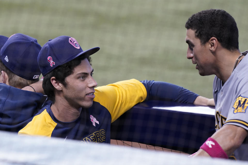 Milwaukee Brewers' Christian Yelich, left, talks to a teammate during the ninth inning of a baseball game against the Miami Marlins, Sunday, May 9, 2021, in Miami. (AP Photo/Marta Lavandier)