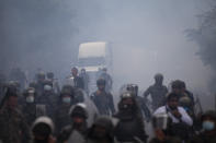 Guatemalan soldiers and police chase groups of migrants amid tear gas cloud at a roadblock on the highway in Vado Hondo, Guatemala, Monday, Jan. 18, 2021. The roadblock was strategically placed at a chokepoint on the two-lane highway flanked by a tall mountainside and a wall leaving the migrants with few options. (AP Photo/Sandra Sebastian)