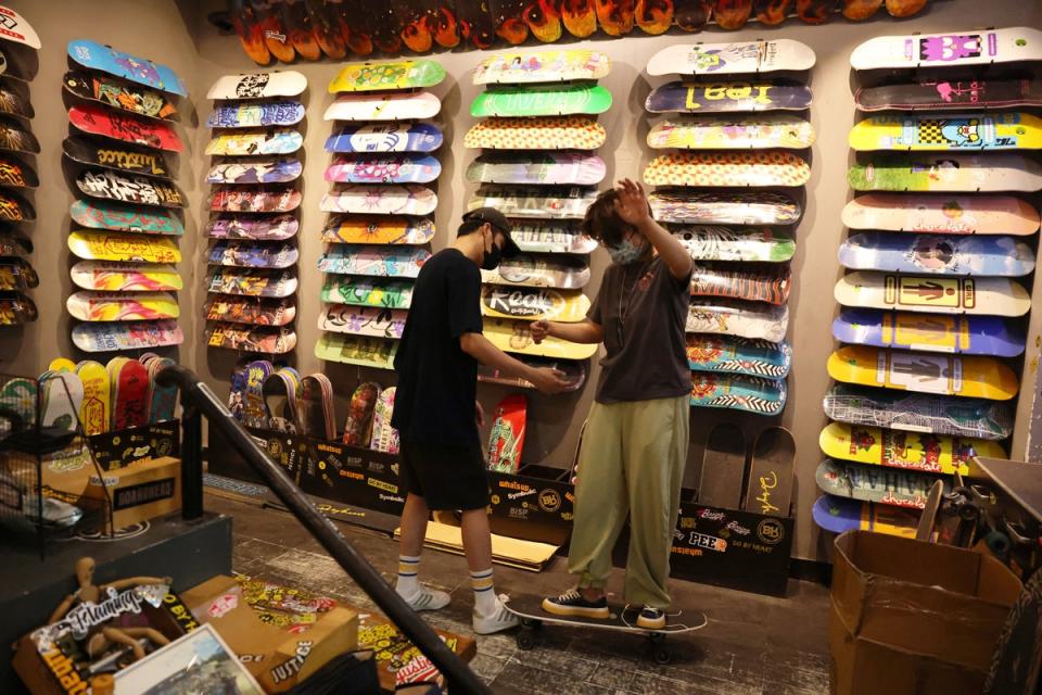 A customer tries on a surfskateboard at the Burning Ice Skateboard shop, in Beijing (Reuters)