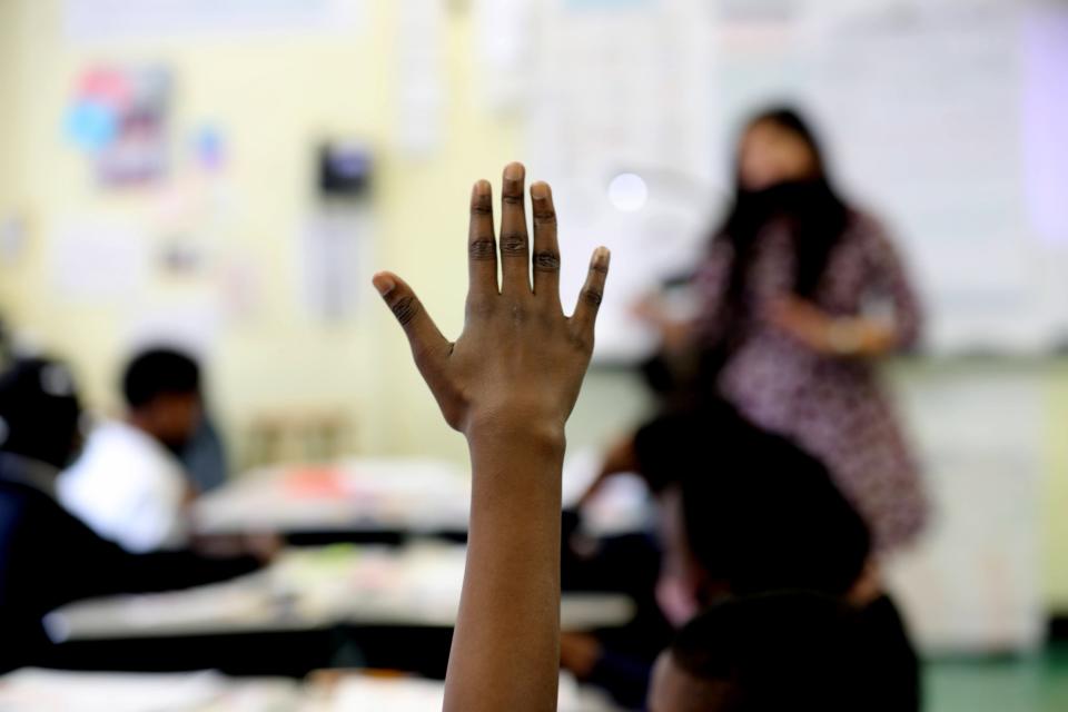 A fourth-grade student in New York City raises her hand during math class on Oct. 28, 2021. Tens of thousands of public school students are getting extra days off this month as exhausted teachers take vacation time, prompting administrators to close schools.
