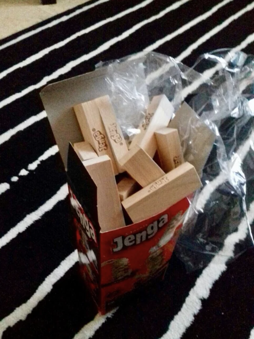 The Jenga pieces are put in the box randomly, so they don't fit together and are spilling out of the box