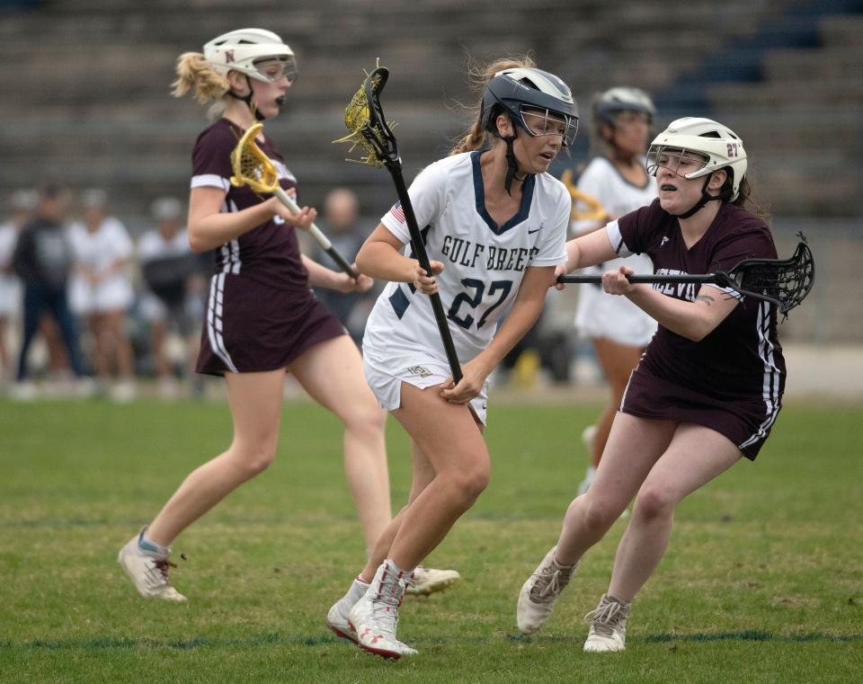 Gulf Breeze High School's Chloe McMillion (No. 27) fights past the Niceville defense during the girls' lacrosse district match on Wednesday, April 12, 2023. 