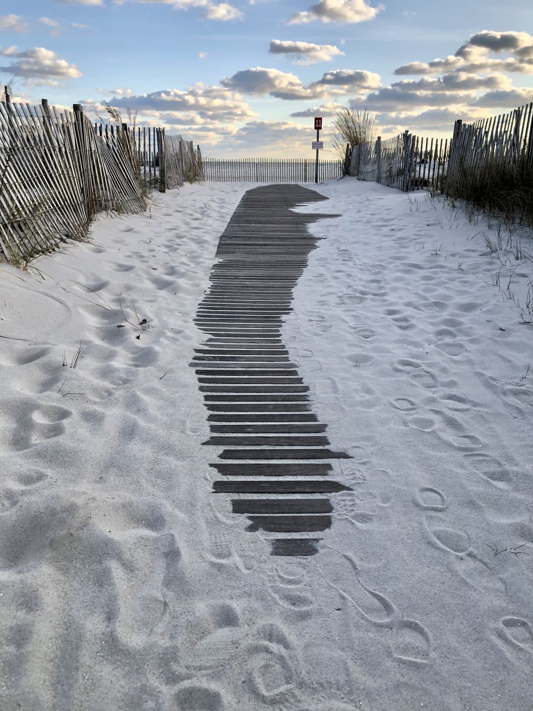 cape may at sunset with wooden walk lined by a fence over white sand