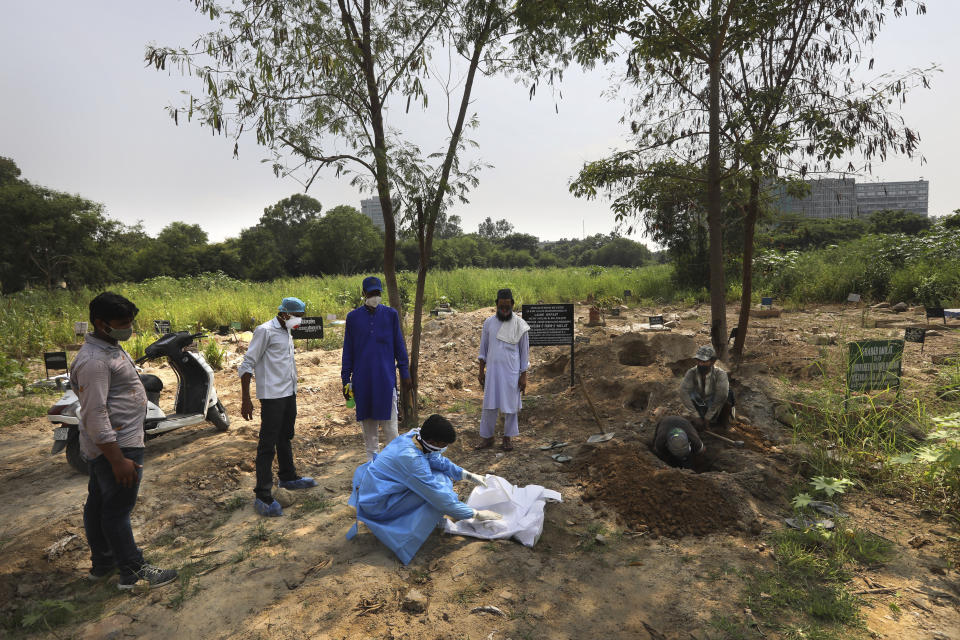 A man wearing personal protective equipment places the body of his three-month-old son who died of COVID-19 for burial in New Delhi, India, Wednesday, Sept. 16, 2020. India is now second in the world with the number of reported coronavirus infections with over 5.1 million cases, behind only the United States. Its death toll of only 83,000 in a country of 1.3 billion people, however, is raising questions about the way it counts fatalities from COVID-19. (AP Photo/Manish Swarup)