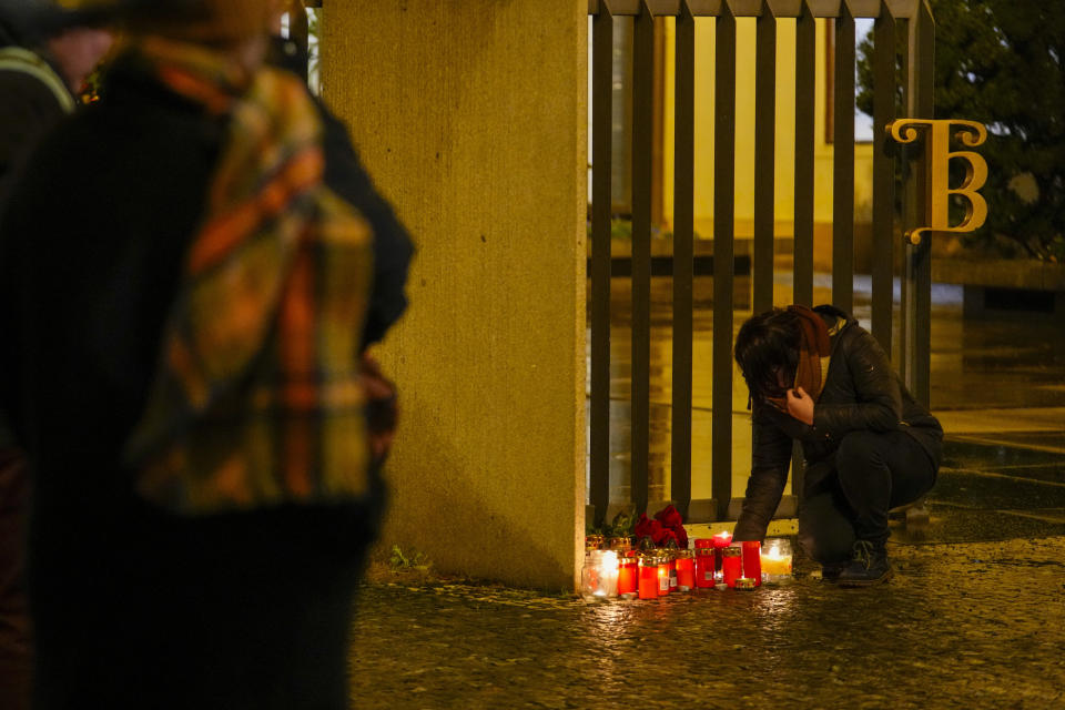 A person lights candles outside the building of Philosophical Faculty of Charles University in downtown Prague, Czech Republic, Thursday, Dec. 21, 2023. A mass shooting in downtown Prague killed several people and injured others, and the person who opened fire also is dead, Czech police and the city's rescue service said Thursday. (AP Photo/Petr David Josek)