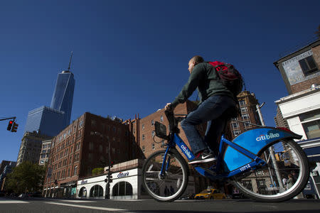 FILE PHOTO: A man rides a Citibike as he passes a Citibank ATM in the Manhattan borough of New York, October 10, 2015. REUTERS/Eduardo Munoz/File Photo